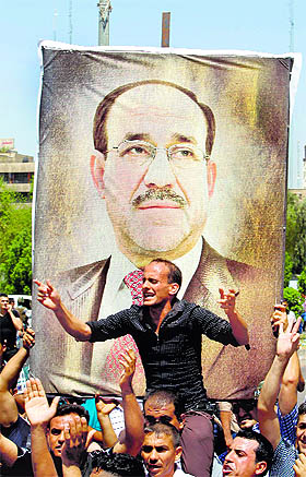 People display a portrait of Iraqi PM Nuri al-Maliki as they gather in support of him in Baghdad on Monday. 
