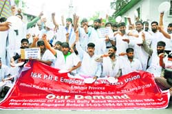 Public Health Engineering employees wear black bands during a protest against the government in Srinagar on Tuesday. Tribune photo: Amin War