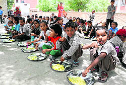 Schoolchildren enjoy their mid-day meal at a school in Bathinda