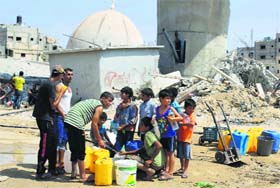 Palestinian children collect water during a five-day truce in Gaza on Thursday
