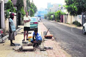 Workers lay tiles on the footpath outside his residence