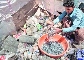 Slum-dwellers sort out highly infected used syringes and catheters at a slum in Srinagar.