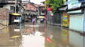 A man walks through a waterlogged street after rainfall in Sriangar.