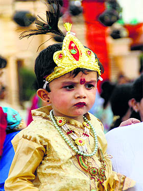 dressed as Lord Krishna, to a temple during the Janmashtami celebrations in Ludhiana on Sunday