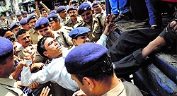 Policemen arrest a protesting member of the BP Ed and MP Ed Unemployed Association at Parade Ground in Dehradun on Sunday