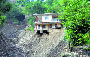 A house at a danger point after a cloudburst in Dharampur in Mandi