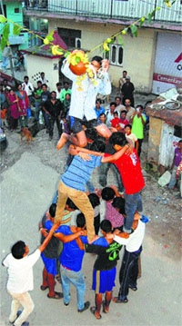 Devotees form a human pyramid to reach a clay pot containing butter during the celebrations of Janmashtami in Dharamsala on Monday.
