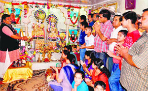 Devotees and a priest offer prayers and hymns to Radha and Krishna on Janmashtami in Haridwar on Monday.