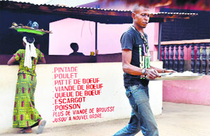 A waiter walks past the menu painted on a wall reading the restaurant doesnt serve bush meat anymore, in compliance with the recommendations of the Ivorian ministry of health.