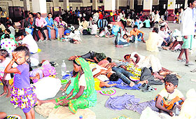 Passengers wait for trains while sitting on the ground at the railway station in Amritsar. 