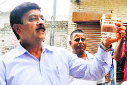 Dr RL Bassan, Civil Surgeon, inspects a water sample at Abadpura in Jalandhar on Tuesday
