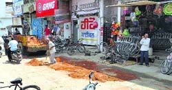 A man fills potholes on the Railway road with mud ahead of Chhapar Mela.