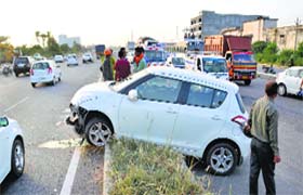 Commuters take a look at the damaged Swift and tavera that hit a couple on GT Road in Jalandhar on Wednesday