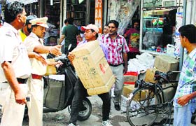 The tehbazari staff of the MC take away stationery items displayed by the book shop owners outside their shops at Mai Hiran Gate