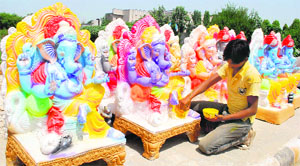 An artist gives final touches to an idol of Lord Ganesha ahead of Ganesh Chaturthi at a roadside in Amritsar on Thursday