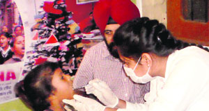 A dentist examines a girl during a free dental camp at Prayaas International School in Bathinda on Thursday.