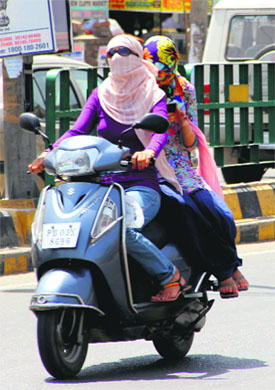 Girls cover their faces while riding a two-wheeler to protect themselves from the heat in Bathnida on Thursday.