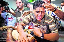 The father of one of the three children from the al-Rifi family killed in an Israeli military strike, grieves over the body of his son at Gaza citys Al-Shifa hospital on Thursday