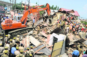 The police, CRPF and civil defence workers carry out rescue work after collapse of a residential house at Hyderpora Chowk in Srinagar on Friday.