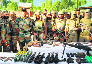 Police and Army soldiers display arms and ammunition recovered from a militants hideout in Hafruda forest area of Handwara in Kupwara district on Friday.