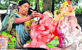 A woman gives final touches to statues of Lord Ganesha at Chakrata Road in Dehradun on Friday as Ganesh Chaturthi approaches. 
