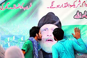 Supporters of cleric Tahir-ul-Qadri kiss his portrait on a banner hung at an anti-government protest site in front of Parliament in Islamabad on Friday. 