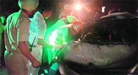 Members of a rescue team try to take out the bodies of the accident victims from the car.