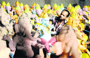 An artisan gives the final touches to idols of Lord Ganesha ahead of Ganesh Chaturthi in Ludhiana.