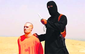 A masked Islamic State militant holding a knife stands next to James Foley at an unknown location