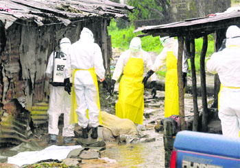 Health workers with protective clothing prepare to carry an abandoned dead body that presented symptoms of Ebola at Duwala market in Monrovia. To control the Ebola epidemic spreading through Western Africa, Liberia has quarantined remote villages at the epicentre of the virus. This evokes memory of medieval Europe’s “plague villages”