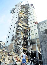 A Palestinian man looks up at the remains of an Italian apartment block that was destroyed by an Israeli air strike in Gaza on Tuesday