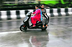 Women ride a scooter amid rain in Bathinda on Wednesday.