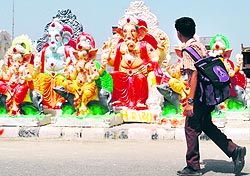 A school child has a look at Lord Ganeshas statues for sale at a roadside on the eve of Ganesha Chaturthi in Amritsar on Thursday