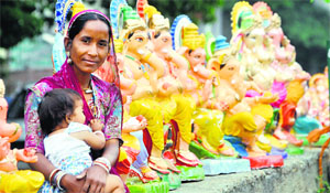 A woman selling idols of Lord Ganesha awaits customers in Jammu on Thursday.