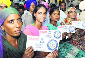 Account holders show kits that they received under the Pradhan Mantri Jan Dhan Yojna in Bathinda on Thursday. All kits carry a photo of CM Parkash Singh Badal.