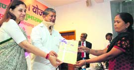 Union Minister Maneka Gandhi and Chief Minister Harish Rawat give bank account documents to a woman in Dehradun in Thursday.