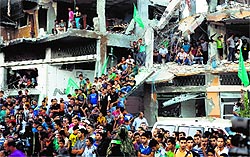 A crowd of Palestinians stand in the rubble of a building that was destroyed during fighting between Hamas militants and Israel in Shejaiya on Thursday