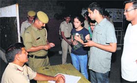 Police personnel check the identity cards of students at a hostel gate at Panjab University in Chandigarh on Friday.