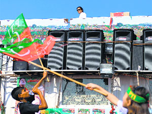 Supporters of Imran Khan wave party flags as Imran (top, background) walks onstage at the site of an anti-government protest in front of Parliament in Islamabad on Friday.