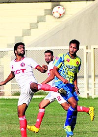 Players of Punjab Police (blue) and JCT (white) vie for the ball in Jalandhar on Saturday. 