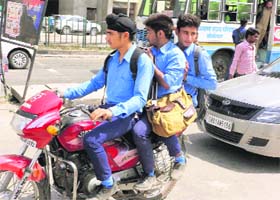 Schoolboys triple ride a two-wheeler on the Chandigarh-Ambala Highway in Dera Bassi