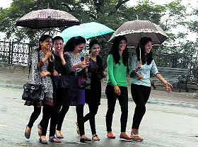 Girls walk with umbrellas during rain in Shimla on Sunday.
