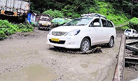 A vehicle crosses a potholed road at Lalpani in Shimla. Tribune photo:  Amit Kanwar 