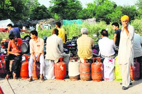 People wait in a queue to get their LPG cylinders refilled on the outskirts of Jammu