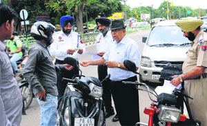 A traffic marshal and police personnel check the documents of a commuters vehicle at Phase VII in Mohali on Monday.