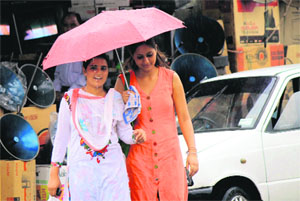 Girls get under an umbrella to protect themselves from rain in Jammu on Monday 