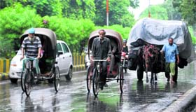 Rickshaw-pullers and a horsecart proceed on Mall Road during rain in Amritsar on Tuesday.