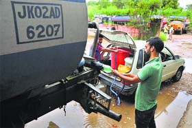 Residents fill water in buckets from a tanker in Jammu