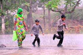 Children enjoy themselves in the rain along with their mother near Kot Shamir in Bathinda on Wednesday.