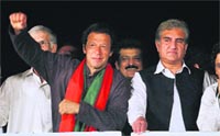 PTI chief Imran Khan (L) acknowledges his supporters by raising his arm as his party leader Shah Mahmood Qureshi looks on during a protest in Islamabad, on Wednesday. AP/PTI 
